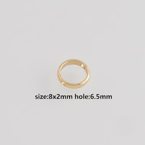 May include: A gold-colored ring with a circular design. The ring has a size of 8x2mm and a hole size of 6.5mm. The ring is set against a plain white background.