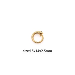 Może przedstawiać: Złoty wąż z czarnymi oczami, o wymiarach 15x14x2,5 mm.