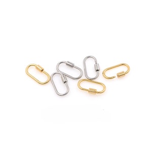 May include: A set of six oval-shaped metal clasps, with a mix of silver and gold finishes. The clasps are open and ready to be attached to a chain or other jewelry.