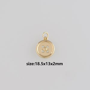 Pode incluir: Um berloque de botão dourado com um design em forma de cruz no centro. O berloque é redondo com uma argola na parte superior. Mede 1,85 cm x 1,3 cm x 0,2 cm. O texto "size:18.5x13x2mm" é visível.