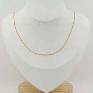 Può includere: Una collana a catena d'oro con un delicato design a catena a pallini. La catena è esposta su un busto di manichino bianco.