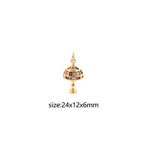 May include: Gold-toned lamp charm with pink and clear rectangular stones. The charm is 24mm x 12mm x 6mm.
