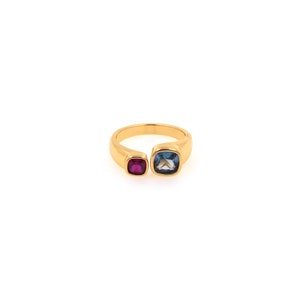 Puede incluir: Un anillo de oro con una piedra azul y una piedra roja. El anillo está abierto por un lado.