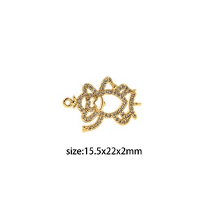 May include: Gold-toned metal charm with a detailed design featuring clear rhinestones. The charm is shaped like a stylised flower with a loop at the top for attaching to jewellery. The charm measures 15.5 x 22 x 2 mm.