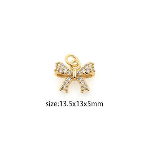 May include: Gold-tone bow charm with clear crystal embellishments. The charm measures 13.5 x 13 x 5 mm.