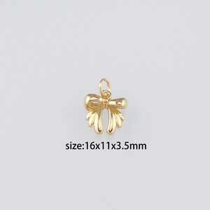 Peut inclure: Breloque en métal doré en forme de nœud avec une boucle en haut pour l'attacher à des bijoux. Le breloque mesure 16x11x3,5 mm.