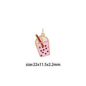 Könnte beinhalten: Goldfarbener Anhänger mit einem rosa und weißen emaillierten Boba-Tee-Becher mit rotem Strohhalm. Der Anhänger ist 22x11,5x2,2 mm groß.