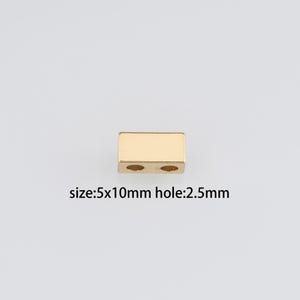 Puede incluir: Conector metálico dorado con dos agujeros, que mide 5x10mm con un agujero de 2,5mm.  size:5x10mm hole:2.5mm