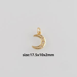 Puede incluir: Colgante de media luna dorada con tres cristales en forma de estrella. El colgante tiene un lazo para sujetarlo a una cadena o pulsera. El texto "size: 17.5x10x2mm" se muestra debajo. Mide 1,75cm x 1cm x 0,2cm.