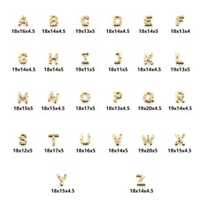 Può includere: Ciondoli con lettere dell'alfabeto dorati con strass trasparenti. Ogni lettera misura circa 18x15 mm.