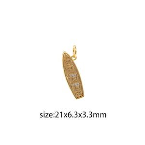 Op de afbeelding: Goudkleurige surfplankbedel met drie kleine, heldere strasssteentjes. De bedel is 21 x 6,3 x 3,3 mm.