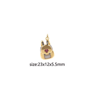 May include: Gold backpack charm with a red heart and clear stones. The charm is 23x12x5.5mm in size.