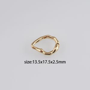 May include: Gold-toned metal ring with an irregular, teardrop-shaped design. The ring measures 13.5 x 17.5 x 2.5 mm.