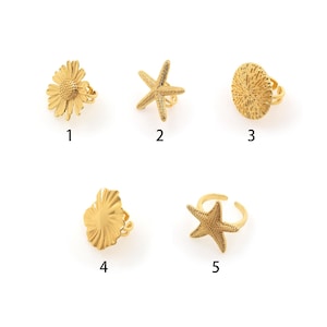 May include: Five gold-toned rings with different designs: a daisy, a starfish, a seashell, a scallop shell, and another starfish. The rings are numbered 1 through 5.
