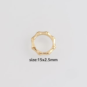 Op de afbeelding: Een goudkleurige ring met een bamboe-ontwerp. De ring is 15 mm x 2,5 mm. De ring is cirkelvormig met een reeks verbonden bamboevormige segmenten. De tekst "size:15x2.5mm" is in het zwart.