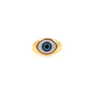 May include: A gold ring featuring a blue eye design. The eye is set within a white oval.