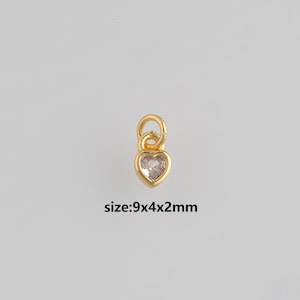 Op de afbeelding: Een goudkleurige hartvormige bedel met een heldere, hartvormige steen in het midden. De bedel heeft een lus aan de bovenkant om te bevestigen. De tekst "size:9x4x2mm" staat eronder.