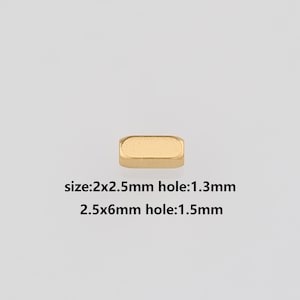 May include: A small, gold-colored rectangular bead. The image includes text indicating the size of the bead is 2x2.5mm with a 1.3mm hole, and 2.5x6mm with a 1.5mm hole. The bead is set against a plain, light background.