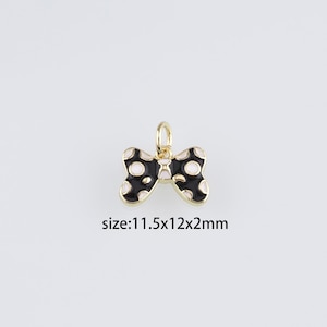Op de afbeelding: Gouden boogbedel met zwart en wit geëmailleerde stippen. De bedel is 11,5 x 12 x 2 mm.