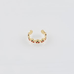 May include: Gold ring with a repeating pattern of red cherries with green stems. The ring is open and adjustable.