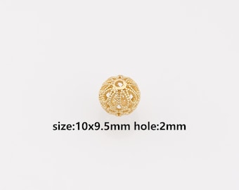 Peut inclure: Une perle sphérique de couleur dorée avec un motif filigrane complexe et une ouverture centrale. La perle présente un design ajouré texturé. Le texte imprimé sous la perle indique : size:10x9.5mm hole:2mm. Ce composant sert à la bijouterie.
