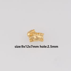 May include: A small, gold-coloured charm in the shape of a bear. The charm measures 9x12x7mm with a 2.5mm hole. The charm is shiny and appears to be made of metal. The text "size:9x12x7mm hole:2.5mm" is printed below the charm.