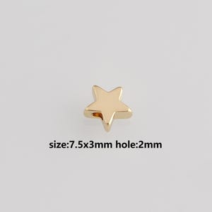 Könnte beinhalten: Eine kleine, goldfarbene sternförmige Perle. Der Text auf dem Bild lautet: Größe: 7,5x3mm Loch: 2mm. Diese Perle wird wahrscheinlich für die Schmuckherstellung oder andere Bastelprojekte verwendet.