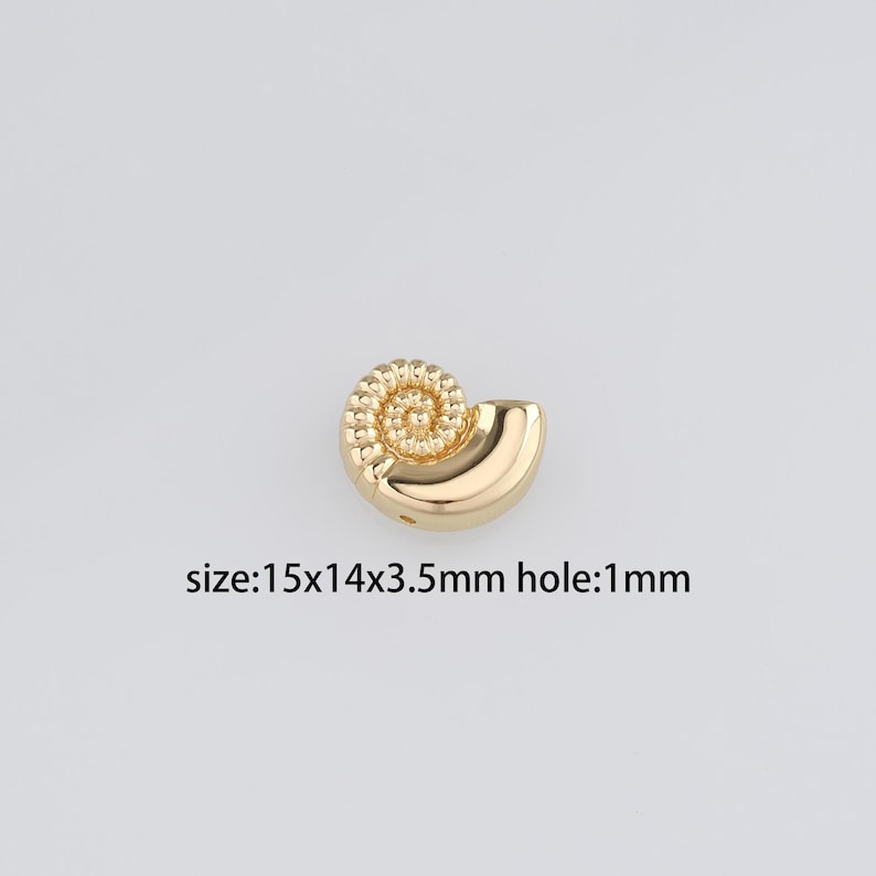 May include: Gold-colored seashell charm with a spiral design. The charm measures 1.5 x 1.4 x 0.35 inches and has a 1 mm hole.