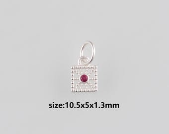 Puede incluir: Un pequeño colgante plateado con un diseño cuadrado de filigrana y una gema roja central. El colgante mide aproximadamente 10,5 x 5 x 1,3 mm. Tiene un pequeño lazo para sujetarlo a una cadena o pulsera.
