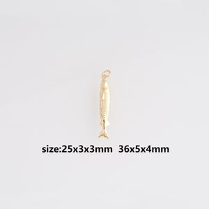 Può includere: Un ciondolo a forma di pesce color oro con un anello nella parte superiore per appenderlo. Il ciondolo presenta squame e pinne dettagliate. Il testo "size:25x3x3mm 36x5x4mm" è visibile.
