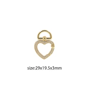 May include: Gold-tone heart-shaped charm with clear rhinestones, featuring a ring at the top. The charm measures 2.9 x 1.95 x 0.3 inches.