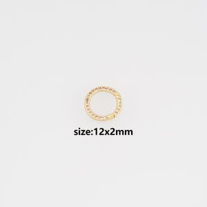May include: A gold-toned circular clasp, adorned with small, clear gemstones around the perimeter. The clasp measures 12mm in diameter and 2mm thick. The text "size: 12x2mm" is below the clasp.