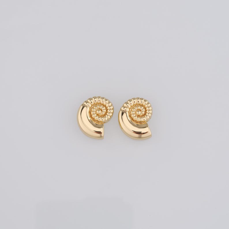 May include: A pair of gold-tone earrings shaped like seashells with a spiral design.