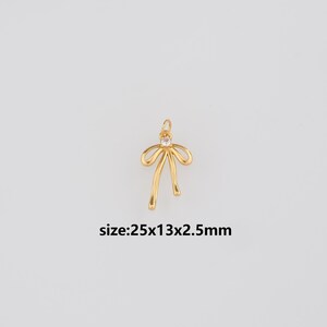 Könnte beinhalten: Ein goldfarbener Schleifenanhänger mit einem kleinen, klaren Edelstein in der Mitte. Der Anhänger misst ca. 2,5 cm x 1,3 cm x 2,5 mm. Der Text "size:25x13x2.5mm" ist darunter abgebildet.