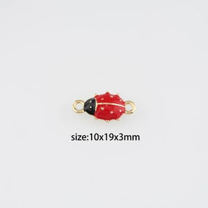 Peut inclure: Un charm coccinelle rouge et noir avec des boucles dorées à chaque extrémité. La coccinelle a des points blancs et mesure environ 10x19x3mm. Le texte "size:10x19x3mm" est en dessous du charm.