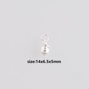 Puede incluir: Un pequeño dije plateado con forma de fruta, posiblemente una pera o una manzana, con una superficie texturizada. El dije incluye un pequeño lazo para sujetarlo a una cadena o pulsera. El texto "size:14x6.5x5mm" es visible.