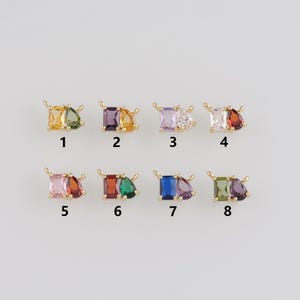May include: Eight small, gold-toned jewellery pieces, each featuring a combination of colourful, rectangular and teardrop-shaped gemstones. The gemstones include shades of yellow, green, purple, pink, red, and blue. Each piece is numbered 1 through 8.