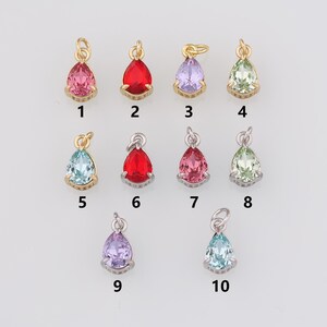 May include: Ten teardrop-shaped crystal charms with gold and silver settings. The charms are in various colours, including red, pink, blue, green, and purple.
