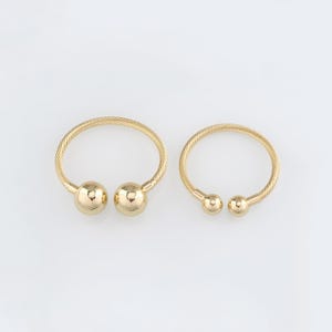 May include: Two gold bangle bracelets with round ball ends. The bracelets are made of a twisted wire design.