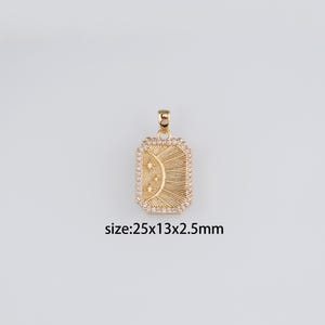 Puede incluir: Colgante dorado con forma rectangular, con un diseño de sol radiante con tres estrellas y un borde de pequeñas piedras transparentes. El colgante mide 25 mm x 13 mm x 2,5 mm.