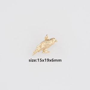 May include: A gold-colored bird charm with a loop for hanging. The charm is 15mm long, 19mm wide, and 6mm thick. The bird is detailed with feathers and a beak. The text "size:15x19x6mm" is below the charm.
