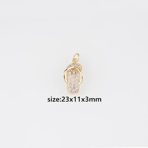 Può includere: Ciondolo dorato a forma di infradito, impreziosito da piccoli cristalli trasparenti. Il ciondolo misura circa 2,3 x 1,1 x 0,3 cm. Il testo "size:23x11x3mm" è visibile.