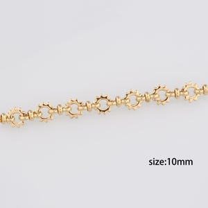 May include: Gold chain with a 10mm size, featuring a repeating pattern of small, round links connected by larger, circular links with a starburst design.
