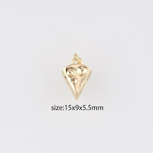 Peut inclure: Un charm doré en forme de part de fromage. Le charm présente trois creux circulaires et une petite boucle en haut pour l'attache. Il mesure environ 1,5 x 0,9 x 0,55 cm.