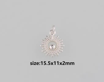 Puede incluir: Un colgante plateado con diseño de sol. El colgante tiene una esfera central rodeada de puntos radiantes. El texto "size:15.5x11x2mm" está debajo.