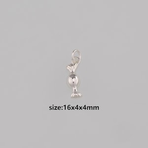 Puede incluir: Un charm plateado con forma de caramelo, con un lazo para colgar. El charm tiene forma de caramelo envuelto, con un centro redondo y extremos retorcidos. El texto "size:16x4x4mm" está debajo.