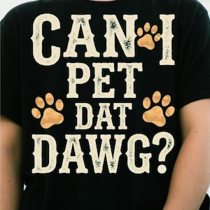 Peut inclure: Un t-shirt noir avec le texte CAN I PET DAT DAWG? imprimé dans une police usée de couleur blanc cassé. Le motif comprend trois empreintes de pattes marron clair disposées autour du texte, réparti sur quatre lignes au centre du vêtement.