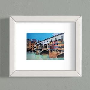 May include: A watercolor painting of a bridge in a city with colorful buildings. The bridge has arches and is over a body of water. The buildings are in the background and are a mix of yellow, orange, and red.