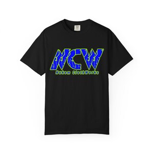 May include: Black t-shirt with a blue and green graphic. The graphic features the letters "NCW" in a cracked, distressed style, with a green outline. Below the letters is the text "Nukem ClothWorks" in green.