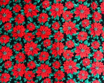 May include: A black fabric with a repeating pattern of red poinsettia flowers and green leaves.